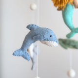 A baby mobile featuring a central mermaid figure surrounded by sea creatures, resting on a neutral-colored background with decorative elements.