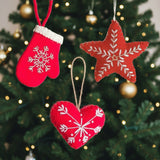 Red Christmas ornaments shaped like a star, heart, and mitten with white snowflake patterns on a white background.