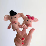Two handcrafted felt duck finger puppets are playfully displayed on the fingers of a hand with red nail polish against a bright white backdrop. Each pink duck puppet features distinct details and is dressed in whimsical honeymoon attire, perfect for interactive storytelling.