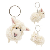A wool felt mini sheep keychain is presented against a plain white background, shown from three distinct angles. This soft, fluffy, off-white felt sheep keychain features small pink-lined ears, a rounded body, and stubby legs. Its minimalist face has tiny black eyes and a darker nose, with a metal clasp attached to the head.