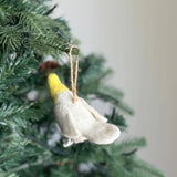 A wool felt cockatiel ornament hangs on a Christmas tree, adding a festive, nature-inspired touch. This handmade felt cockatiel features a bright yellow head and a white body, crafted from wool felt with visible textures. A jute string allows the unique Australian native parrot bird ornament to dangle among the green needles, enhancing its charm.