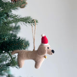 A charming felt Dachshund dog ornament is displayed on a festive Christmas tree. This handmade felt ornament features four adorable Dachshunds in cream, khaki, brown, and black. A playful felt bone is centrally placed on a white felt frame, creating a delightful canine-themed design.