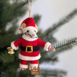 A festive wool felt Santa mouse ornament hangs prominently on a blurred Christmas tree. This handmade felt ornament features a cute mouse dressed in a red and white Santa suit with a black belt and gold buckle. The mouse has beige ears, a white face with black whiskers, and small black eyes, holding a small gold bell in its left hand. A jute string is attached to its hat for easy hanging.