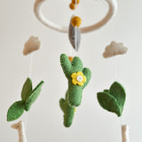 A white felt llama baby mobile is displayed against a plain white background. It features a white felt ring with several small, white wool felt llamas suspended by thin, clear strings. The llamas have a soft, textured appearance, suggesting handmade quality.