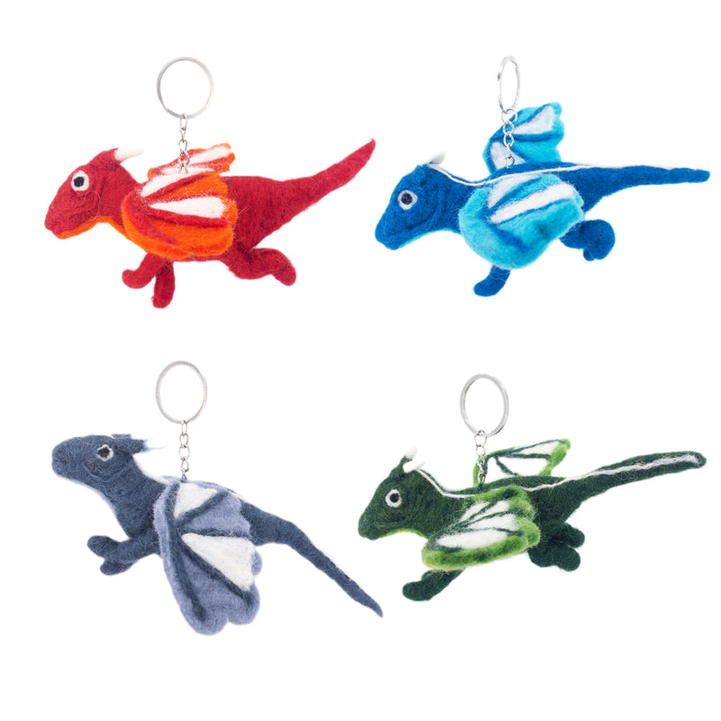 Four handmade felt flying dragon keychains are arranged against a stark white background. The unique handcrafted felt keychains include a red dragon with orange and white wings, a blue dragon with lighter blue and white wings, a gray dragon with white wings, and a green dragon with white wing markings. Each charming felt keychain is fitted with a metal keyring.