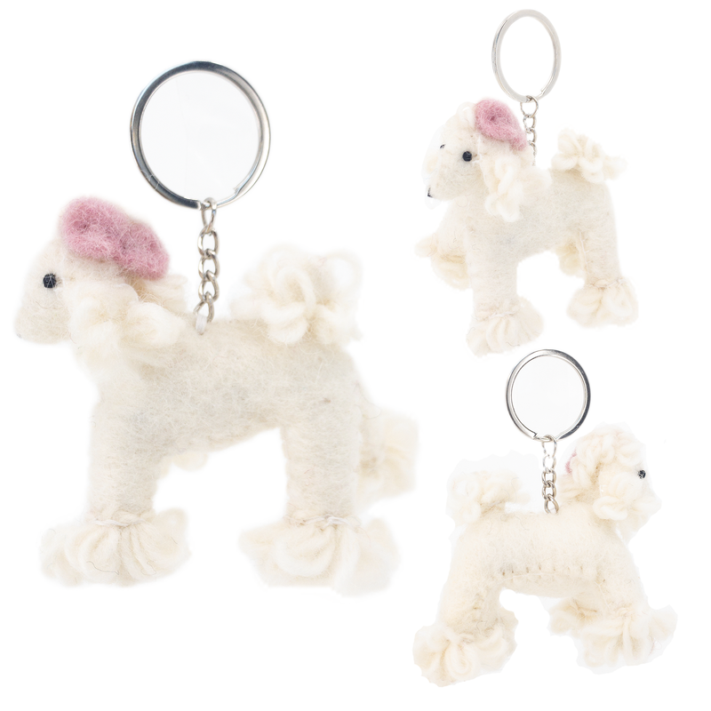 Three wool felt poodle keychains are suspended by metal clasps against a stark white backdrop. Each handcrafted keychain features a fluffy white poodle wearing a pink beret, emphasizing their unique charm.