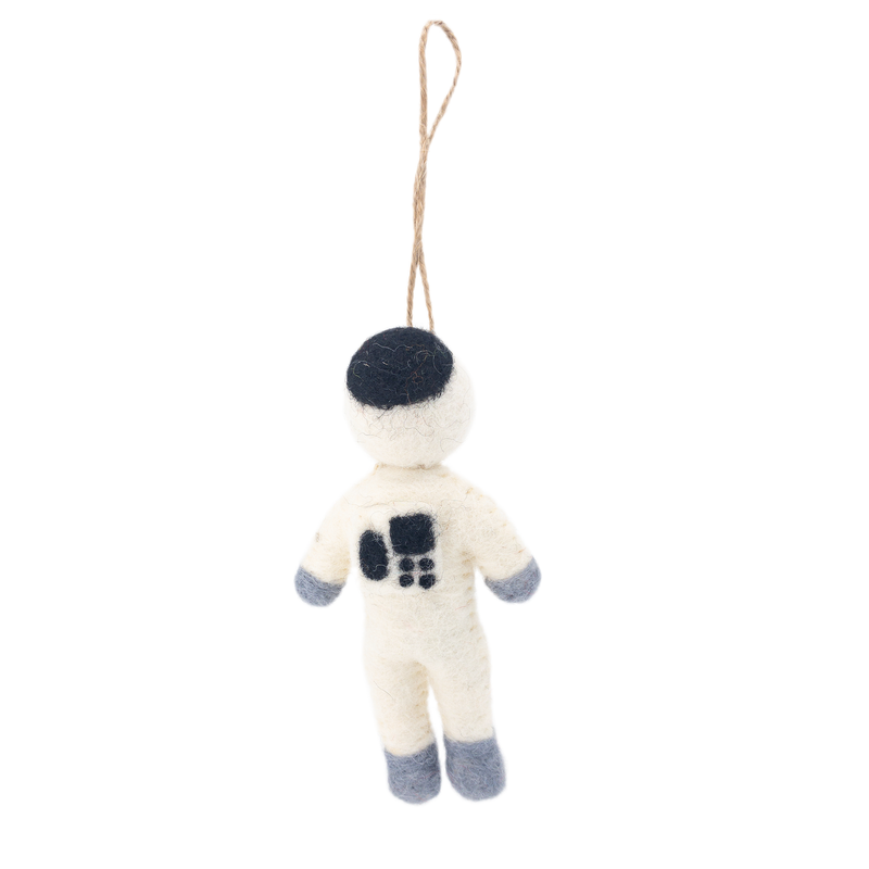 Suspended by a jute string against a plain white backdrop, a needle felted astronaut ornament is showcased. This handmade Christmas ornament features a miniature astronaut with a round, dark gray headpiece and an off-white organic wool felt body. Dark gray organic wool felt forms the astronaut's gloves and boots, while a dark gray square with small black details adds a lifelike design to the front.