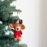 A cute felt reindeer Christmas ornament hangs on a vibrant green Christmas tree, set against a cheerful, bright backdrop. This light brown reindeer features darker brown accents on its antlers and hooves, enhanced by a vibrant red scarf. Its face details include small, round eyes and a stitched nose. The unique Christmas ornament is suspended by a natural jute string.