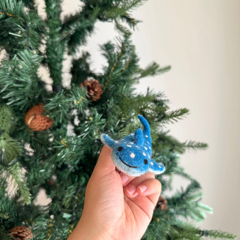 A light blue felt whale shark finger puppet is presented, featuring white spots resembling a starry night sky. This charming handmade felt kids toy includes small fins, a tail, a stitched mouth, and black eyes, ideal for imaginative oceanic adventures.