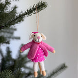 A charming felt mouse ornament from the Mouse Family Ornaments collection hangs by a jute string from an evergreen Christmas tree branch, set against a blurred white background. The white mouse features black eyes, a pink nose, and soft tan hands and feet. It is dressed in a pink dress with beaded accents, a matching pink jacket, and a pink headband.