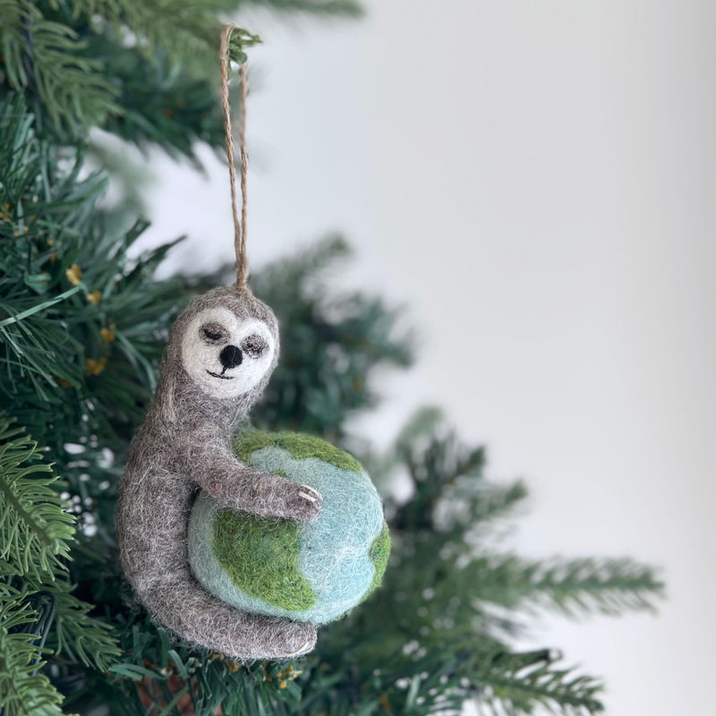 A hand-painted Sloth Embrace: Earth-Holding Decor sculpture features a sloth gently hugging a spherical earth. The earth is rendered with distinct patches of green land and blue water. This unique sloth sculpture is crafted with intricate detail, making it a compelling piece of decor.