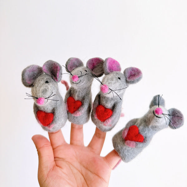 Handcrafted needle felted mouse finger puppets, each holding a heart, are displayed in a female hand against a plain white backdrop. These unique 3D wool felt finger puppets feature gray bodies with pink ears and noses, delicate black whiskers, and a bright red heart.